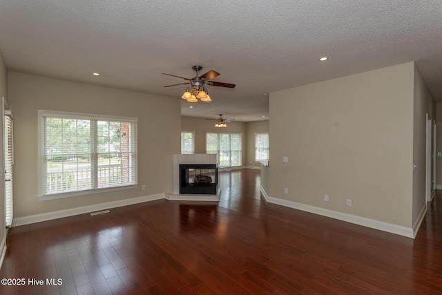 unfurnished living room featuring baseboards, ceiling fan, wood finished floors, recessed lighting, and a textured ceiling