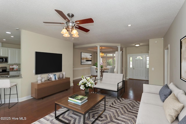 living area featuring ornate columns, a ceiling fan, a textured ceiling, wood finished floors, and baseboards