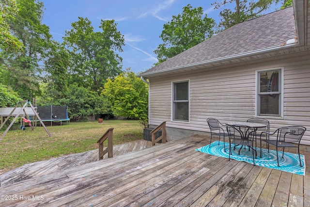 707 Brown Pelican Ln, Hampstead, NC 28443 - wooden deck featuring a trampoline, a lawn, a playground, and outdoor dining area