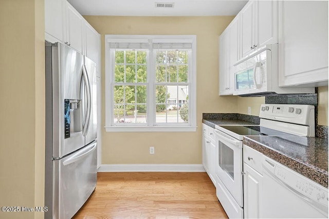 kitchen with white appliances, dark countertops, light wood finished floors, and white cabinets