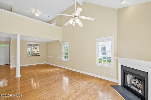 unfurnished living room with a fireplace with flush hearth, baseboards, a ceiling fan, high vaulted ceiling, and healthy amount of natural light