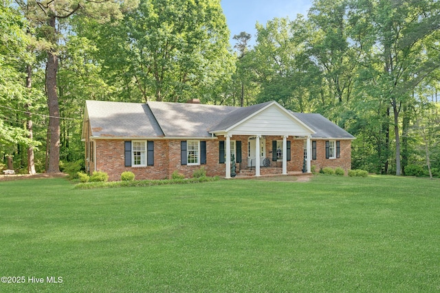 greek revival inspired property with covered porch, a front yard, brick siding, and a shingled roof