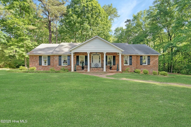 greek revival house featuring a porch, brick siding, and a front lawn