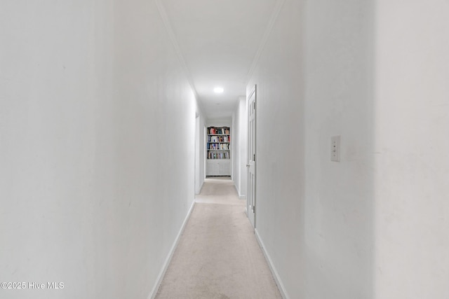 hallway featuring ornamental molding, light carpet, and baseboards