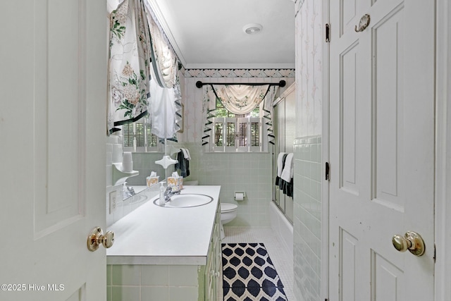 bathroom featuring vanity, toilet, tile walls, tile patterned flooring, and enclosed tub / shower combo