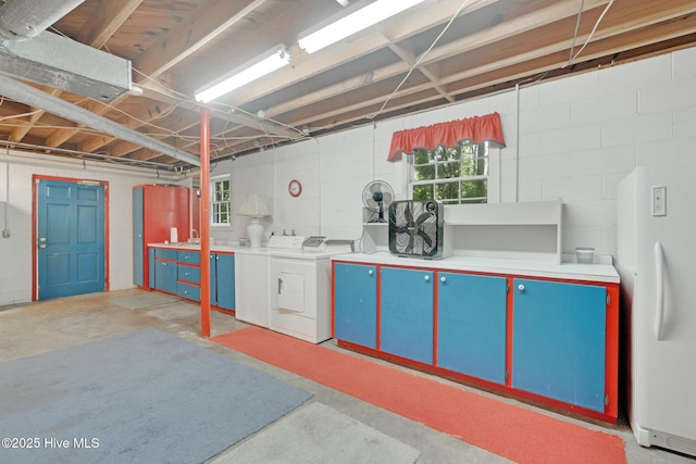 basement featuring independent washer and dryer, freestanding refrigerator, plenty of natural light, and concrete block wall
