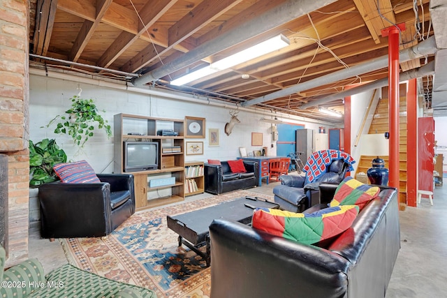 living room featuring concrete floors, concrete block wall, and stairway