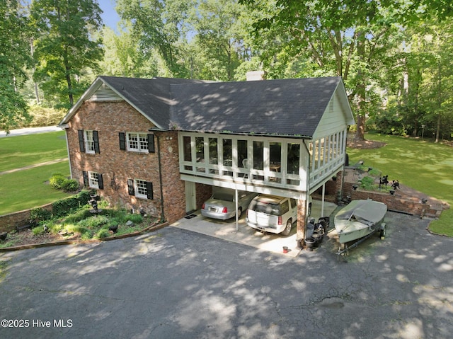 rear view of house with a shingled roof, a chimney, brick siding, and a yard