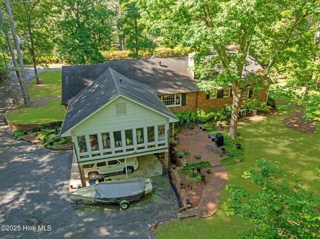 back of house with a shingled roof, asphalt driveway, and a yard