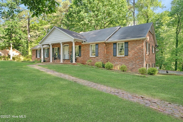 neoclassical / greek revival house with brick siding, covered porch, and a front lawn