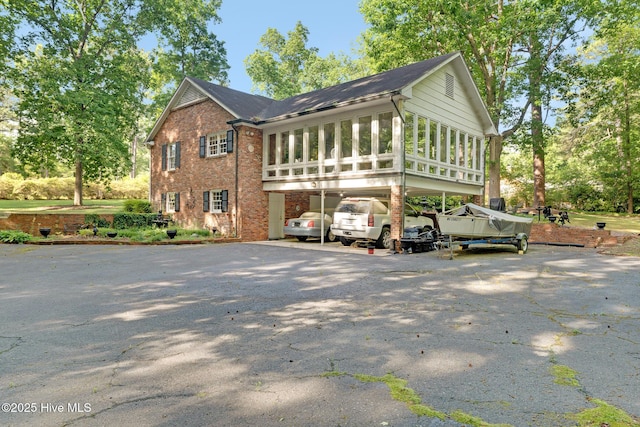 view of side of property with a carport, asphalt driveway, and brick siding