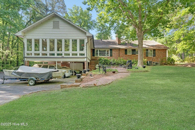 back of property with driveway, a yard, a carport, and brick siding