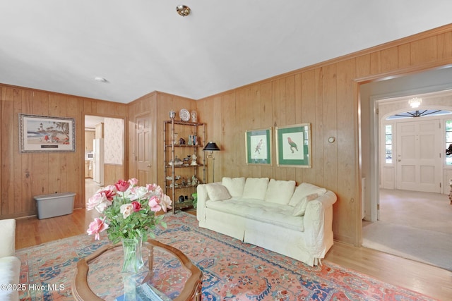 living area with wooden walls, wood finished floors, and ornamental molding