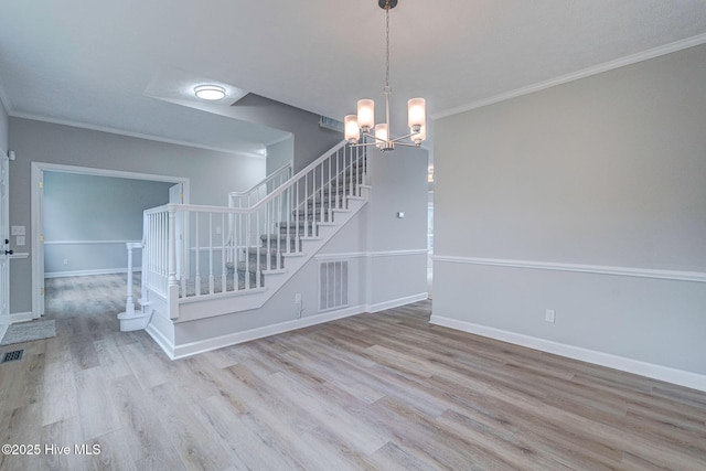 unfurnished room featuring stairway, wood finished floors, crown molding, a chandelier, and baseboards
