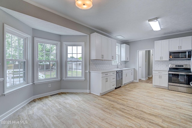 kitchen with appliances with stainless steel finishes, decorative backsplash, light wood-style floors, light countertops, and plenty of natural light