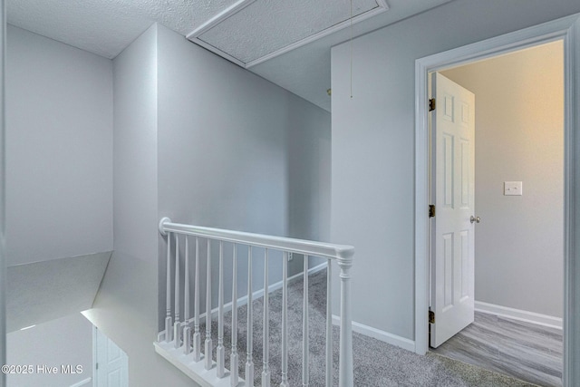 hall with an upstairs landing, attic access, and baseboards
