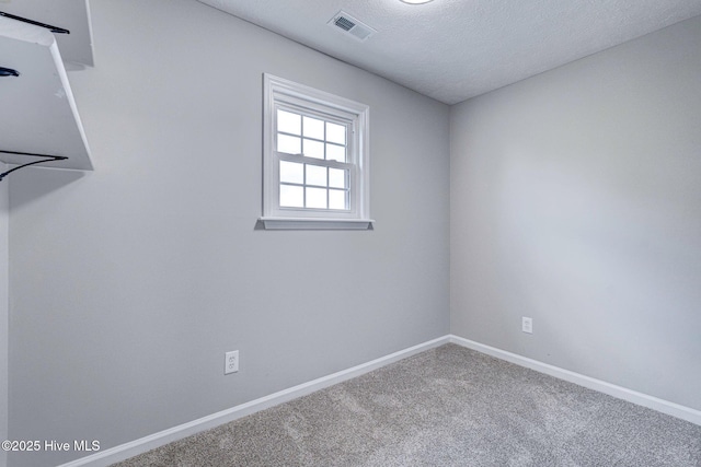 carpeted empty room featuring baseboards and a textured ceiling