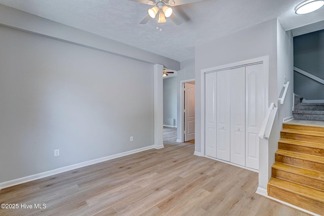 unfurnished bedroom with light wood-style flooring, a closet, baseboards, a textured ceiling, and ceiling fan