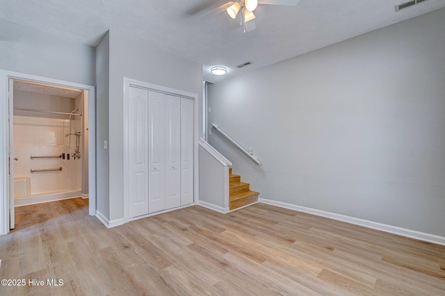 unfurnished living room featuring a ceiling fan, light wood-type flooring, stairs, and baseboards