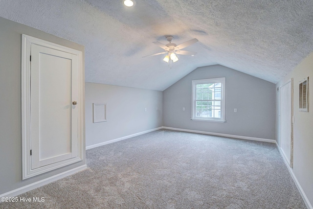 bonus room with carpet flooring, baseboards, lofted ceiling, a textured ceiling, and ceiling fan
