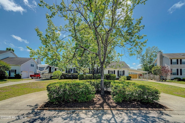 view of front of house featuring driveway, a residential view, a carport, and fence