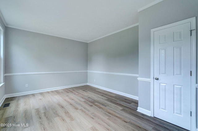 unfurnished room featuring wood finished floors, crown molding, and baseboards