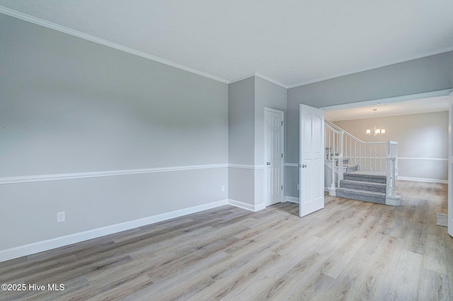 spare room with a chandelier, wood finished floors, ornamental molding, stairs, and baseboards
