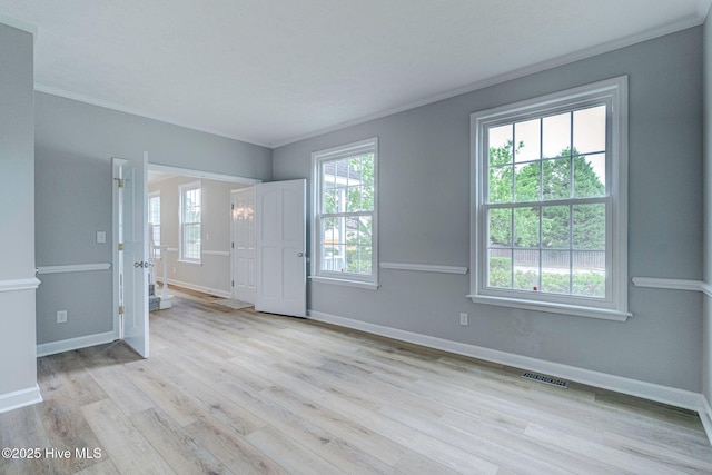 unfurnished room with plenty of natural light, wood finished floors, baseboards, and ornamental molding
