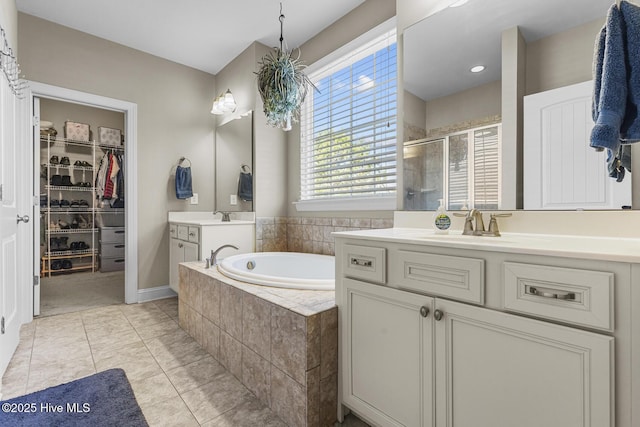 211 Willow Ridge Dr, Holly Ridge, NC 28445 - full bathroom with a stall shower, two vanities, a garden tub, tile patterned floors, and a walk in closet