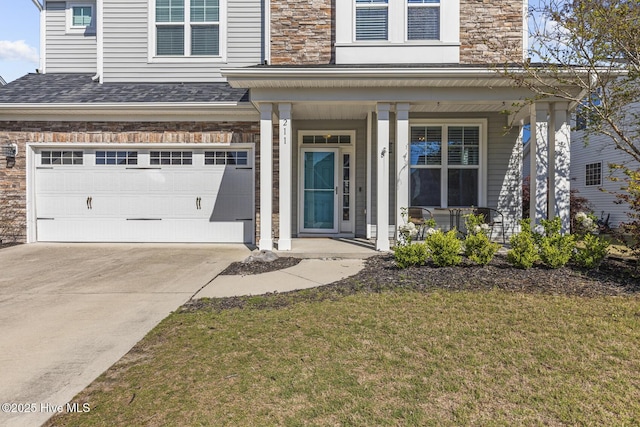 211 Willow Ridge Dr, Holly Ridge, NC 28445 - property entrance with a porch, a garage, concrete driveway, a yard, and stone siding