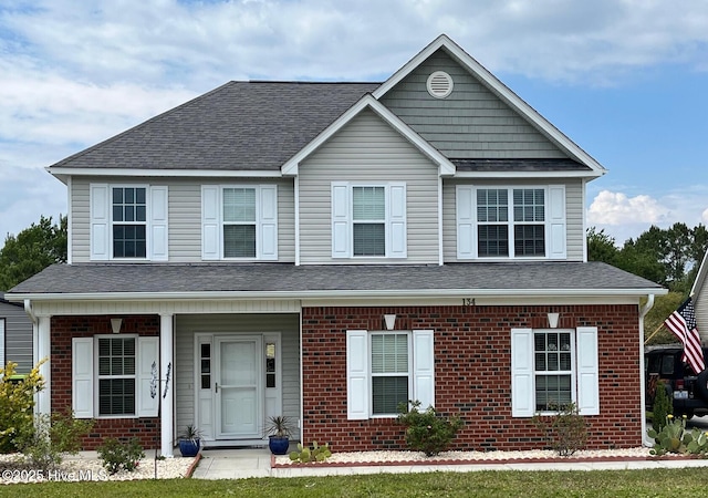 view of front of property featuring brick siding, a shingled roof, and a porch
