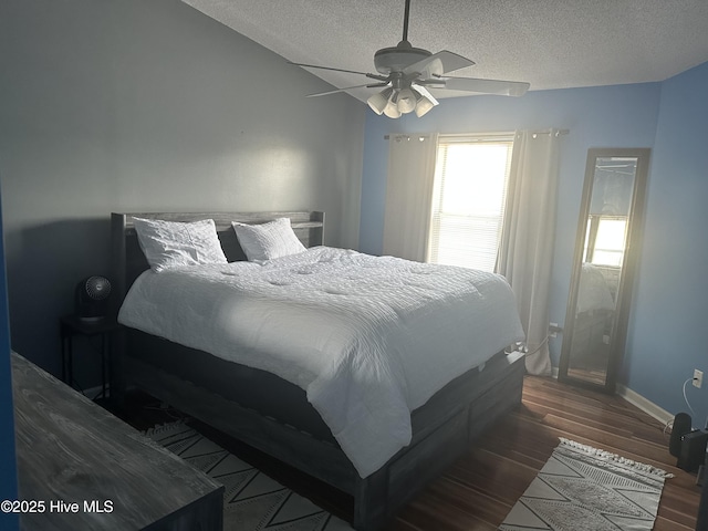 bedroom featuring wood finished floors, a textured ceiling, baseboards, and ceiling fan