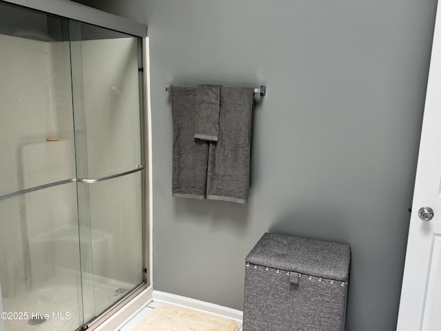 full bathroom with a shower stall and baseboards