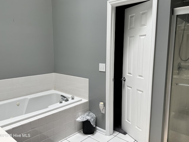 bathroom with tile patterned floors, a bath, a shower with door, and baseboards
