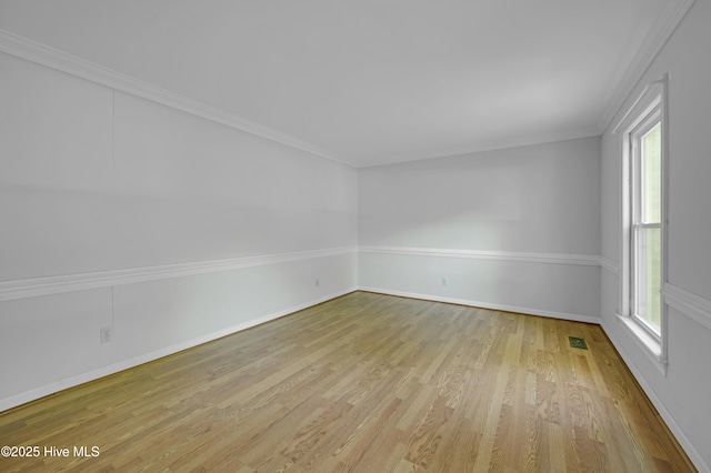 spare room with wood finished floors, baseboards, and crown molding