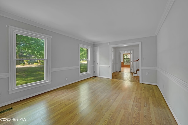 unfurnished room featuring light wood-type flooring, baseboards, crown molding, and stairway