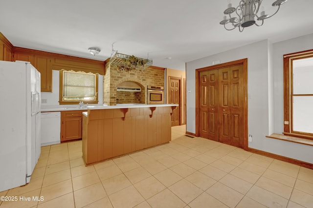 kitchen featuring white appliances, light countertops, a chandelier, and light tile patterned flooring