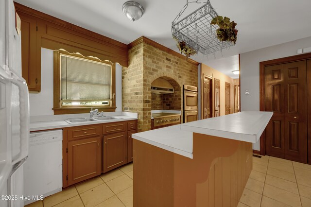 kitchen featuring white dishwasher, a sink, light tile patterned flooring, and extractor fan