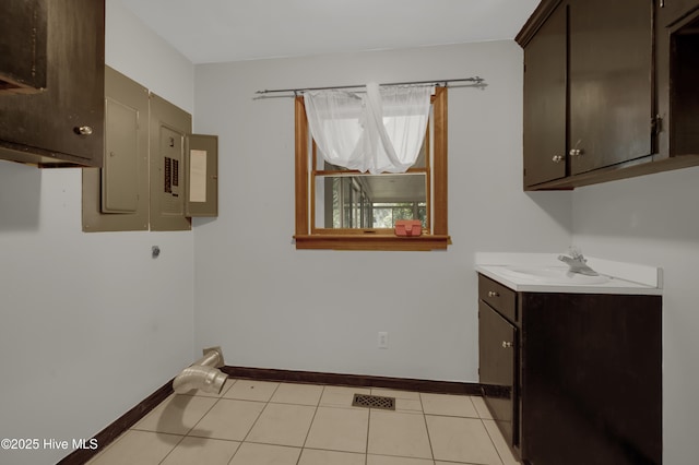 clothes washing area featuring a sink, baseboards, electric panel, light tile patterned floors, and electric dryer hookup