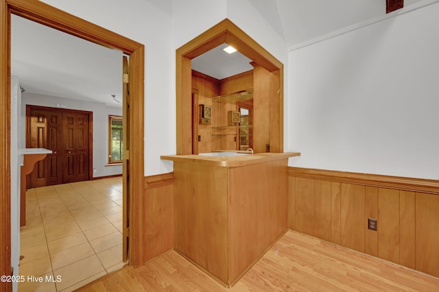 bar area with a wainscoted wall, wood walls, and wood finished floors