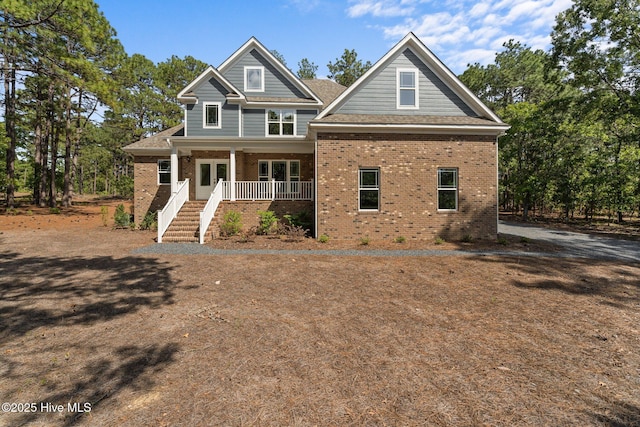 craftsman-style home with a porch, brick siding, and stairway