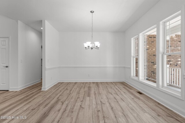 unfurnished dining area featuring light wood-type flooring, a chandelier, and baseboards