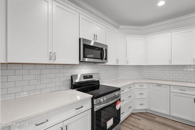 kitchen featuring appliances with stainless steel finishes, white cabinetry, crown molding, light wood-type flooring, and tasteful backsplash