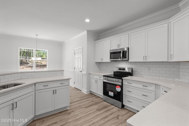 kitchen with appliances with stainless steel finishes, crown molding, white cabinetry, light wood-type flooring, and decorative backsplash
