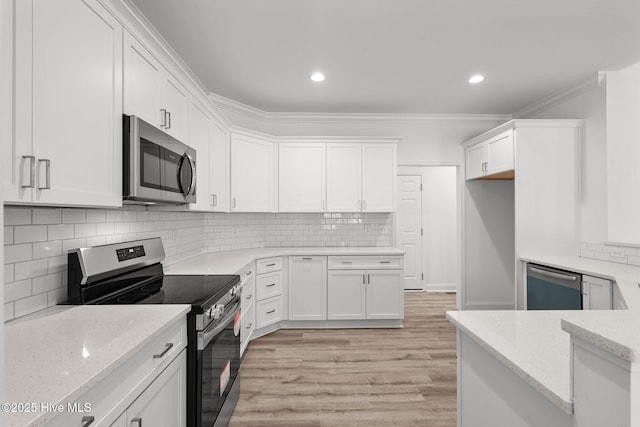 kitchen featuring appliances with stainless steel finishes, light wood-style floors, light stone counters, white cabinetry, and backsplash