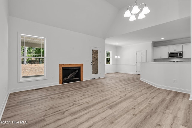 unfurnished living room with a chandelier, a fireplace, light wood-style floors, baseboards, and recessed lighting