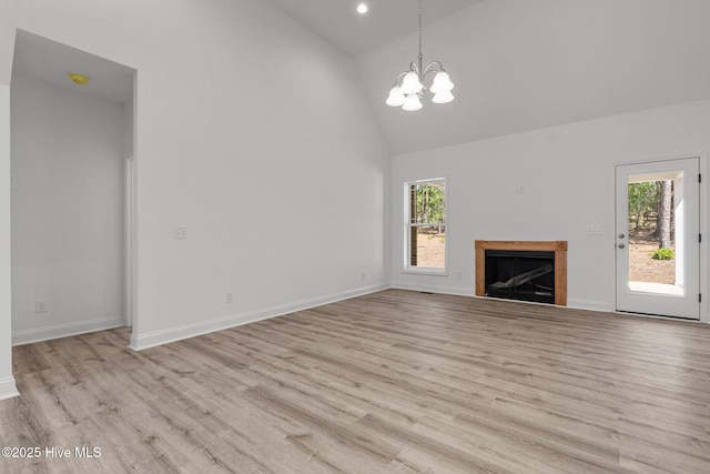 unfurnished living room with high vaulted ceiling, light wood finished floors, a chandelier, plenty of natural light, and a fireplace