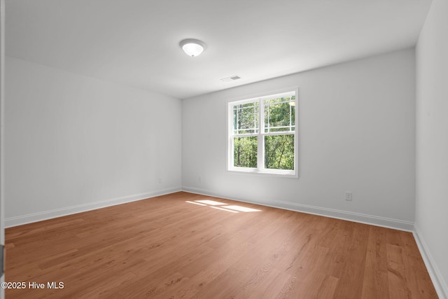 spare room featuring baseboards and wood finished floors
