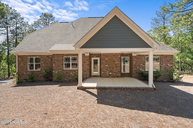 rear view of property with brick siding and a shingled roof