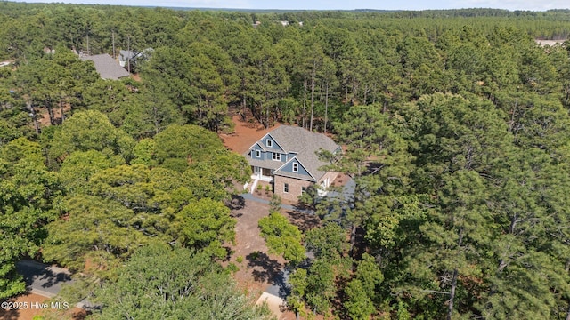 aerial view of property and surrounding area featuring a heavily wooded area
